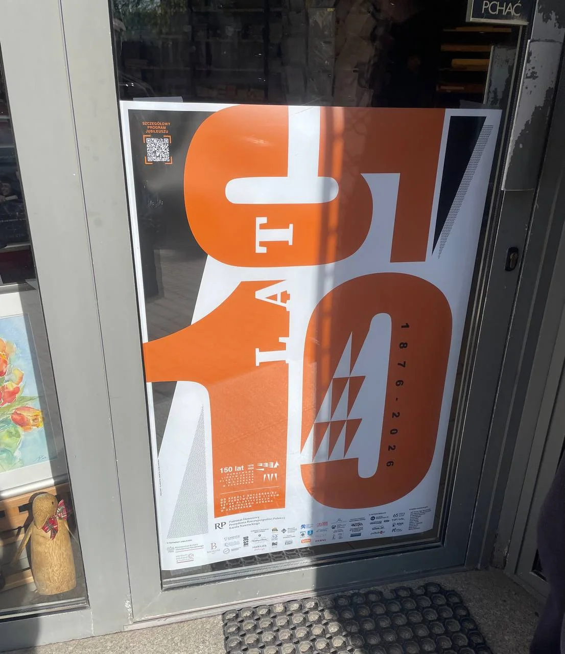 Plakat 150-lecia Liceum Kenara w witrynie sklepu plastycznego na Krupówkach w Zakopanem